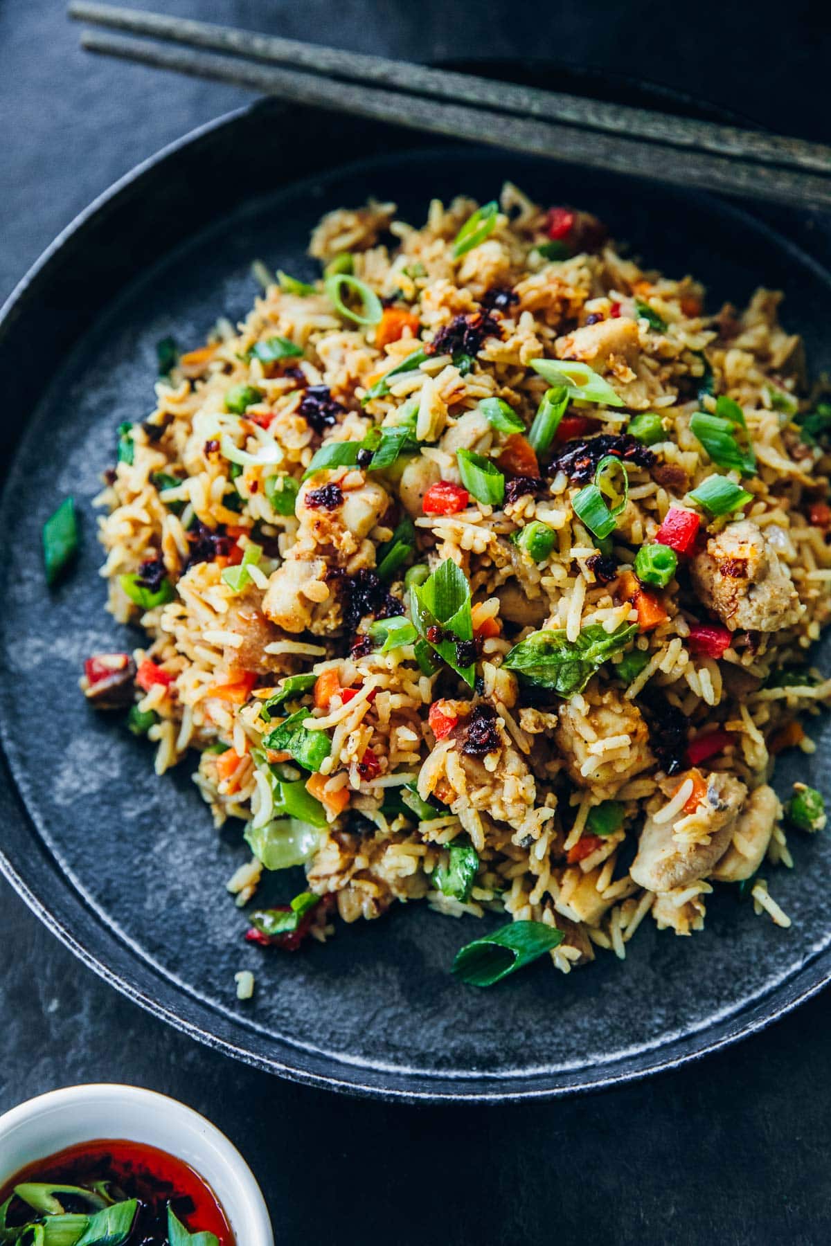 Chicken Fried Rice in a bowl with chopsticks and chilli oil for serving.